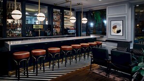 A bar area with a long counter, multiple stools, and a modern chandelier. - Claridge House Chicago, Tapestry Collection by Hilton (Chicago)
