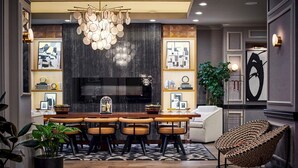 A modern kitchen with a central island, bar stools, a chandelier, and a large flat-screen TV. - Claridge House Chicago, Tapestry Collection by Hilton (Chicago)