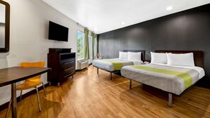 A hotel room with two beds, a desk, a chair, a TV, and a window with curtains. - Studio 6 Portland, OR (Portland)