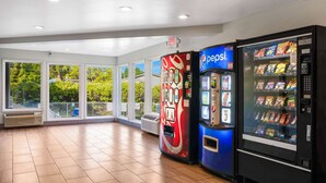 A spacious room with large windows, a Coca-Cola vending machine, a Pepsi machine, and a snack vending machine. - Studio 6 Portland, OR (Portland)