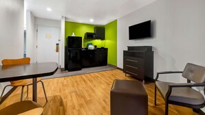 A compact room with a dining table, chairs, a sofa, a TV, a microwave, and a refrigerator. - Studio 6 Portland, OR (Portland)