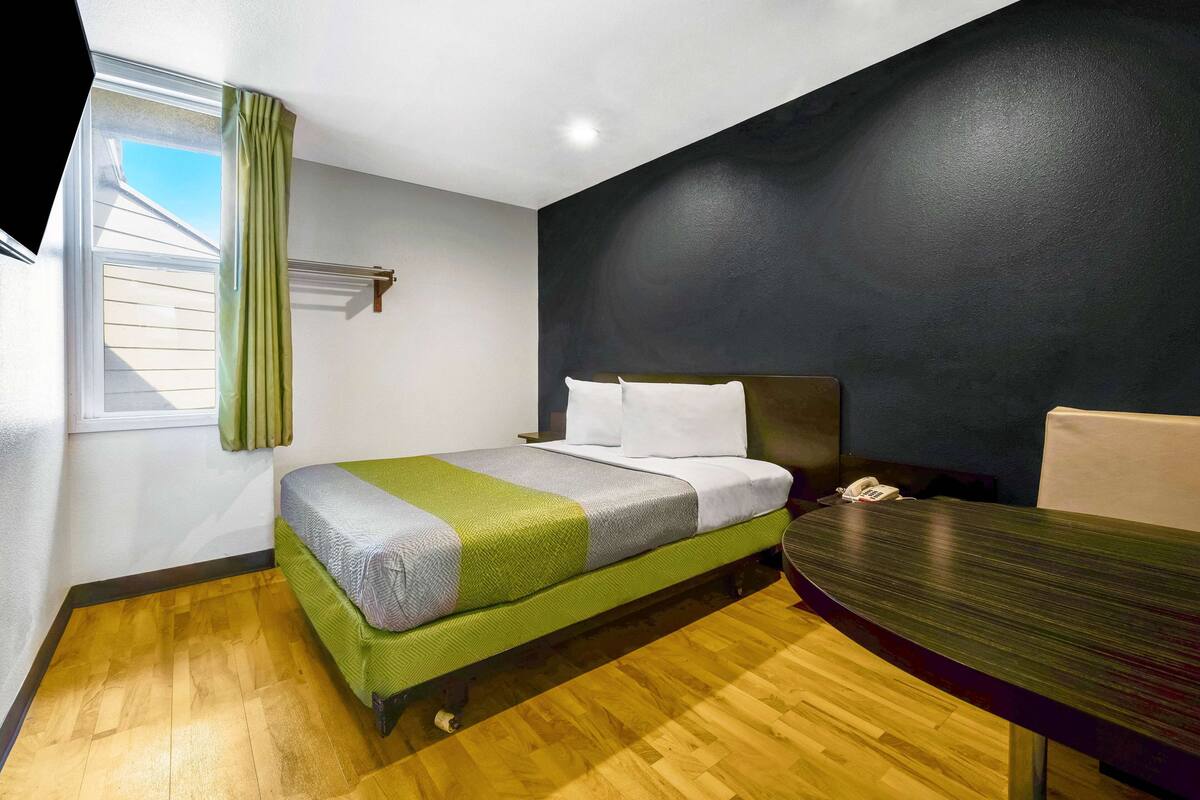 A room with a bed, a table, and a window with curtains.