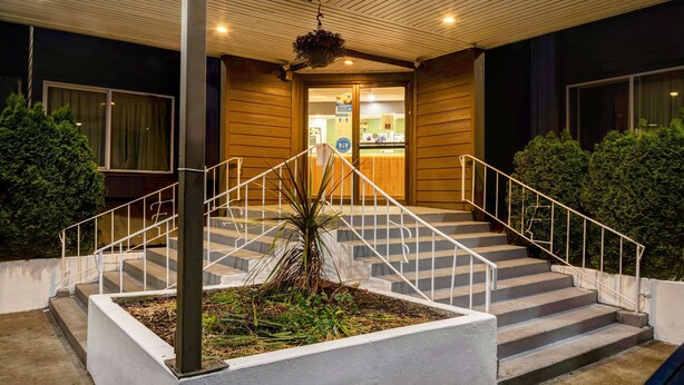 A hotel entrance with a staircase, a hanging planter, and a reception desk. - Studio 6 Portland, OR (Portland)