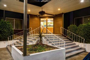 A hotel entrance with a staircase, a hanging planter, and a reception desk.