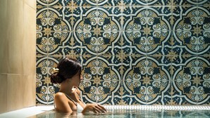 Una mujer en una piscina con un muro de azulejos y un diseño geométrico.