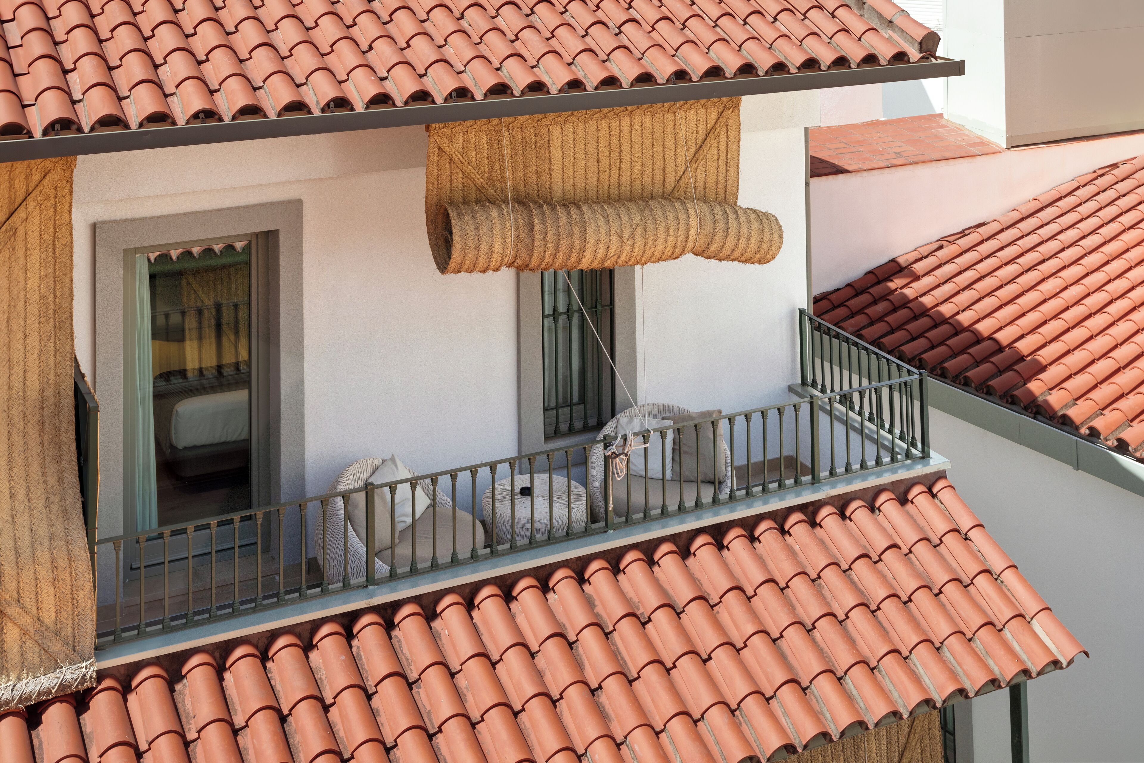 A balcony with terracotta tiles, a window, and a view of the adjacent building.