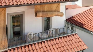 A balcony with terracotta tiles, a window, and a view of the adjacent building.