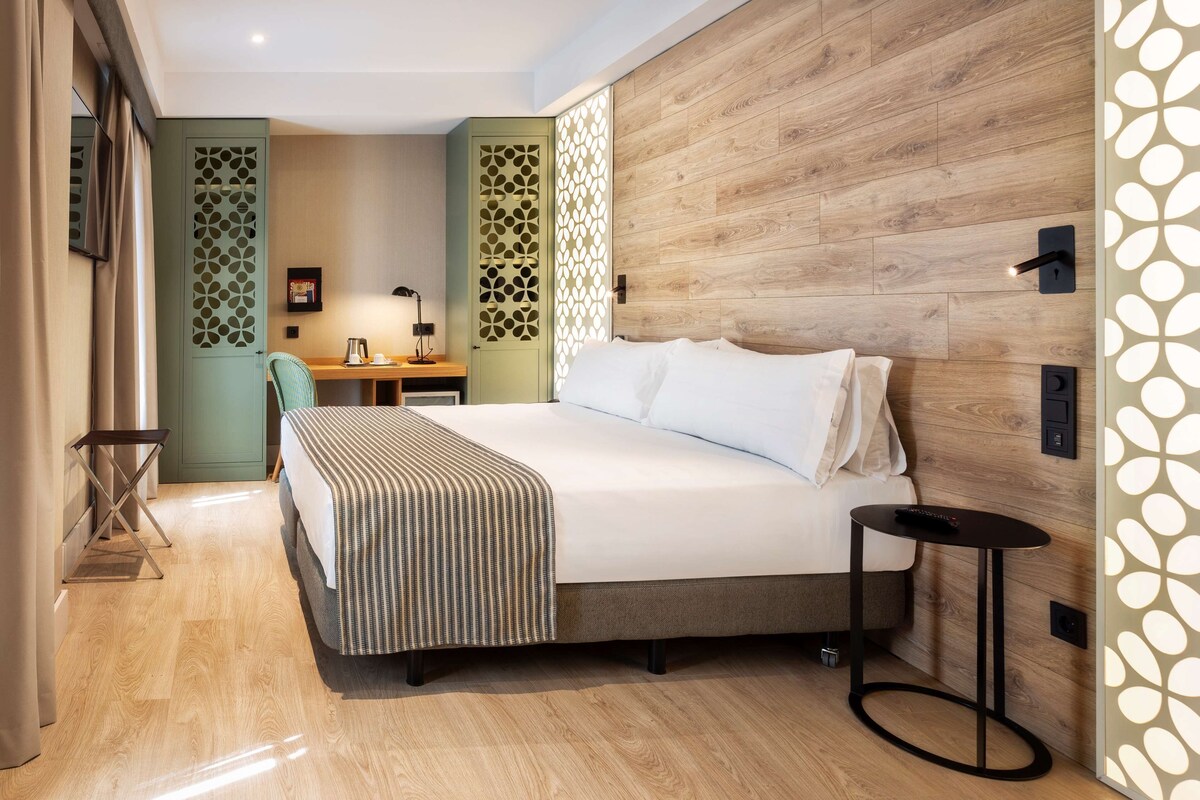 Una habitación de hotel moderna con una cama grande, un escritorio y una silla.