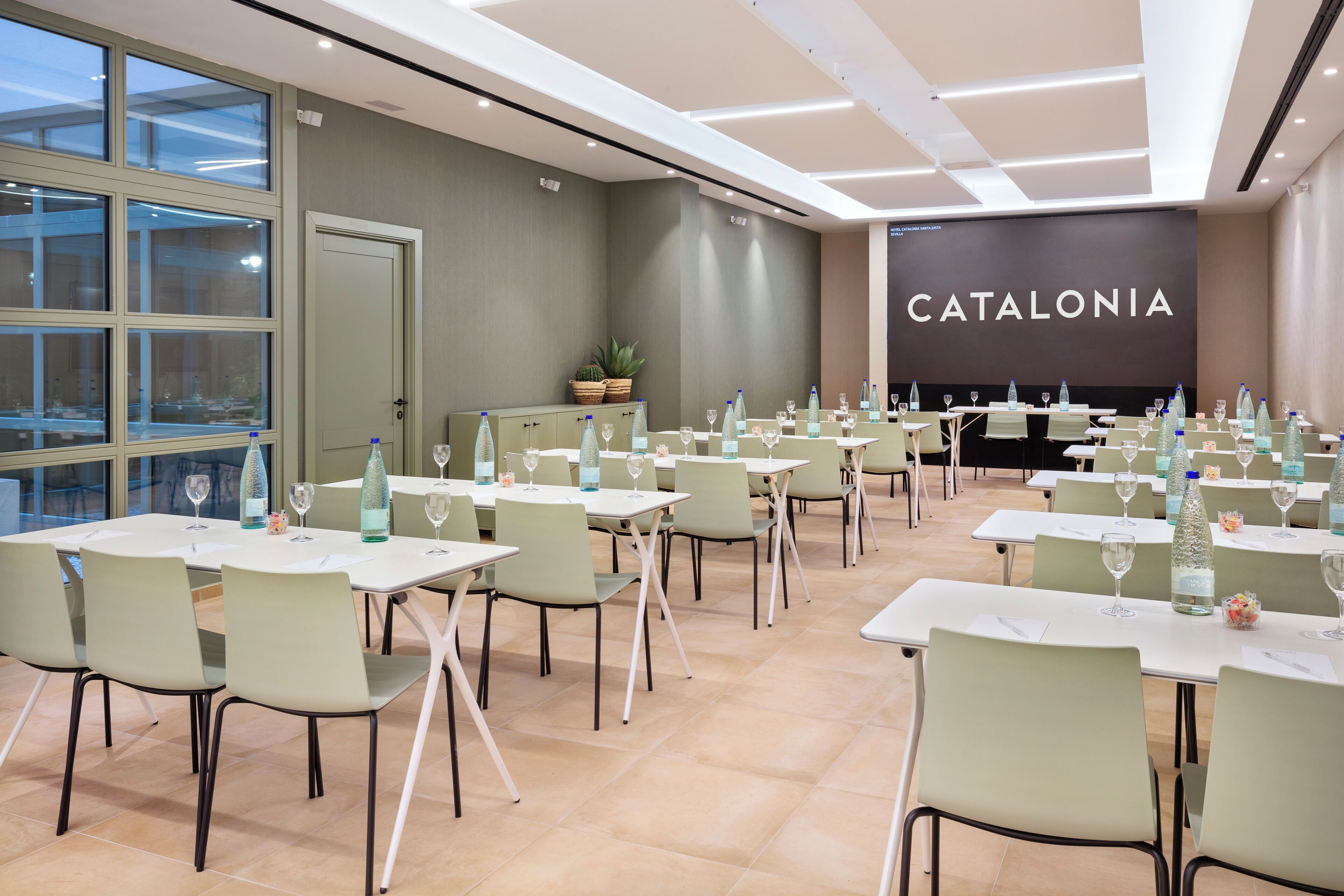 Un salón de conferencias con mesas dispuestas para una reunión, con un gran cartel de 'CATALONIA' en la pared.