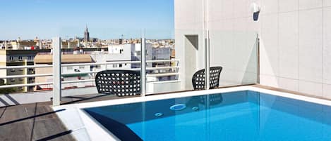 A rooftop pool with a clear view of the cityscape, including a prominent tower.