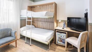 Una cama litera con escalera, un escritorio con televisor, una silla y un refrigerador pequeño.