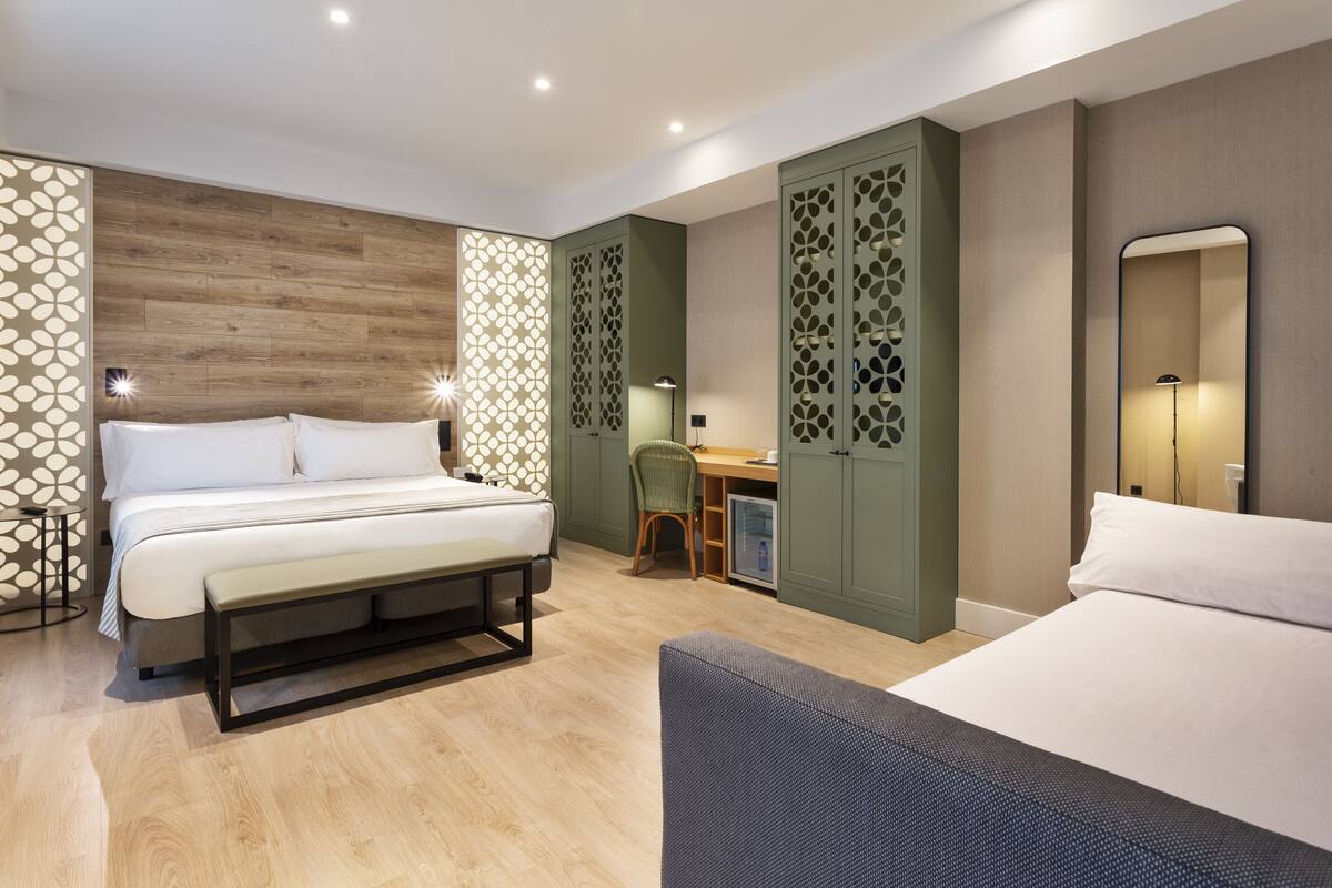 Quarto de hotel com cama, escrivaninha, cadeira e guarda-roupa.