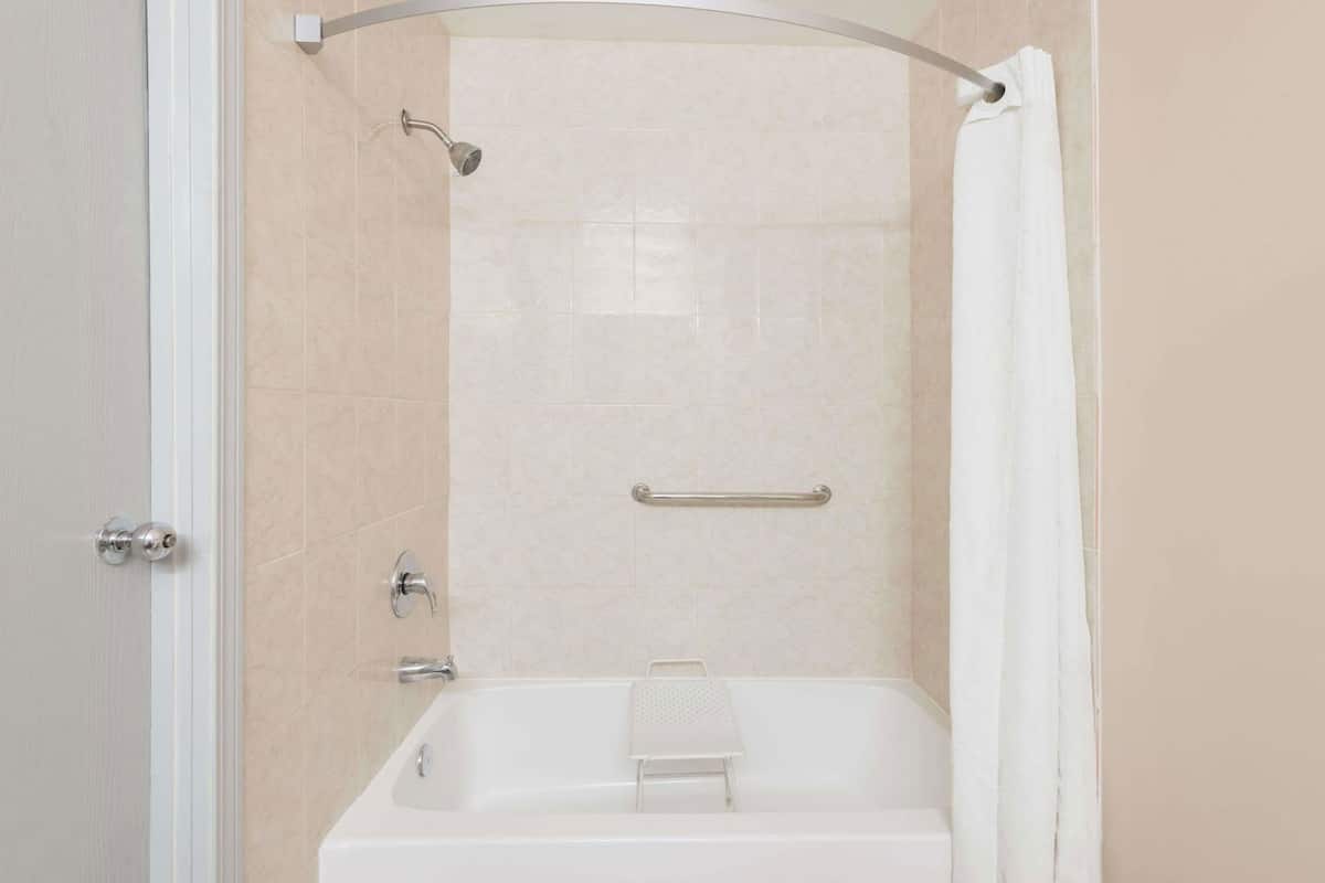 Eine bodenebene Dusche mit Duschbrause, Haltegriff und kleinem Handtuchhalter.