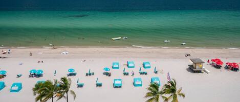 A beach with turquoise water, a sandy shore, and several beach chairs and umbrellas.