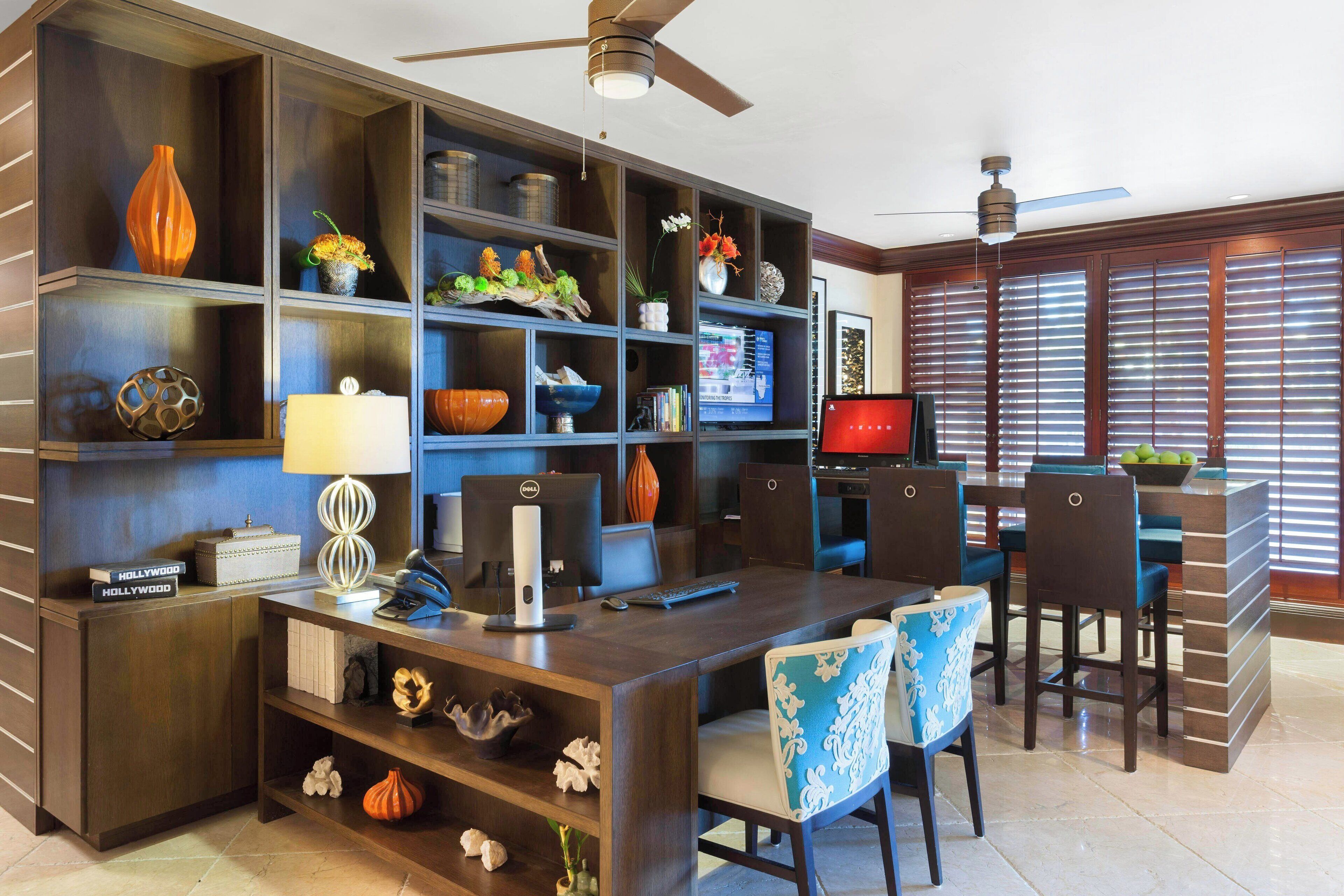 A modern home office with a desk, computer, and shelves with decorative items.
