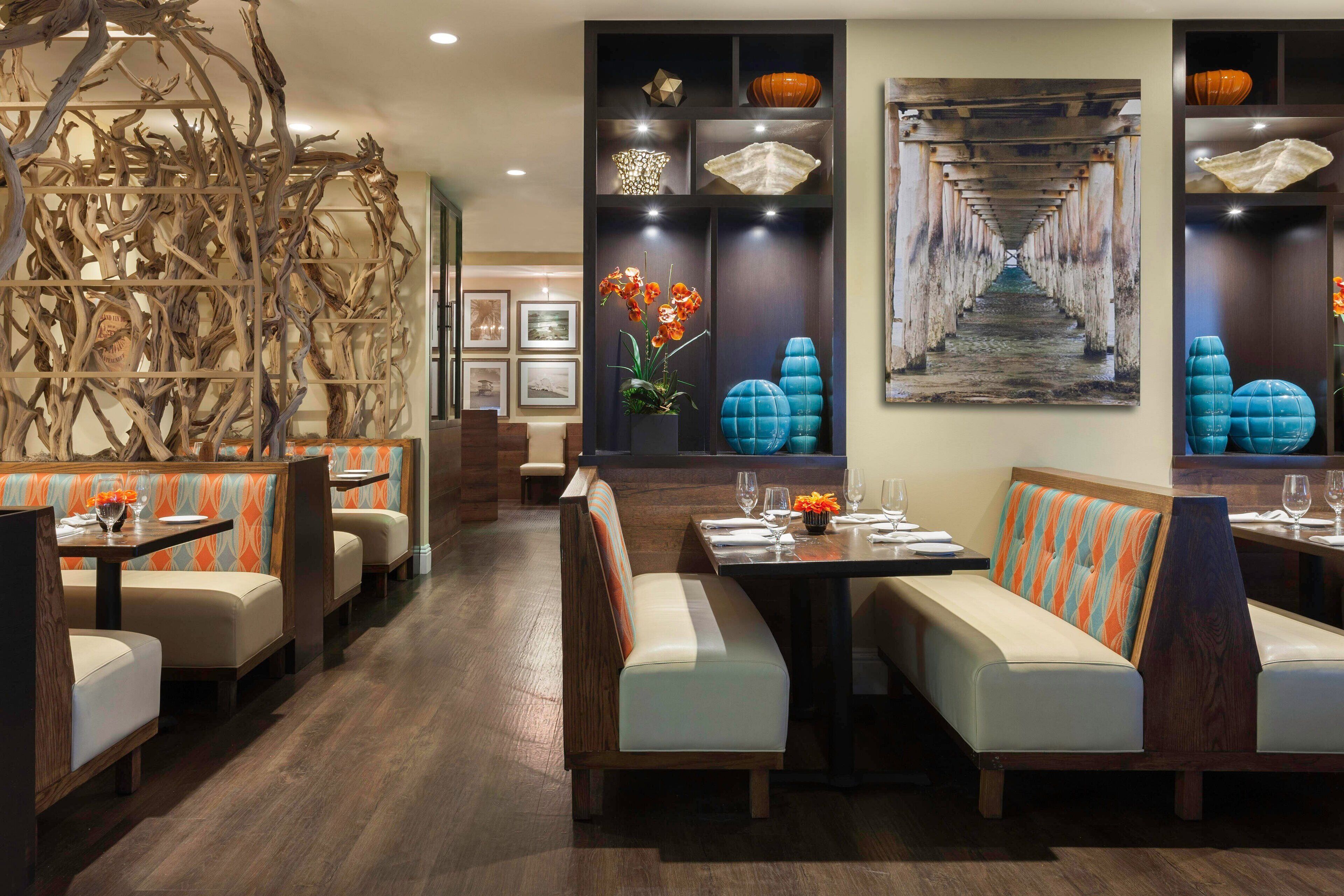 Un restaurant avec des banquettes et des tables, une décoration en bois et des œuvres d’art encadrées accrochées aux murs.