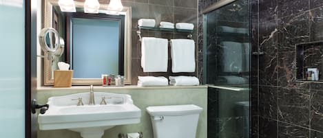 A bathroom with a sink, mirror, toilet, and a glass shower enclosure.