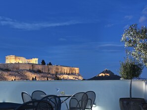 Une terrasse avec des places assises extérieures, offrant une vue sur d’anciennes ruines et une montagne.