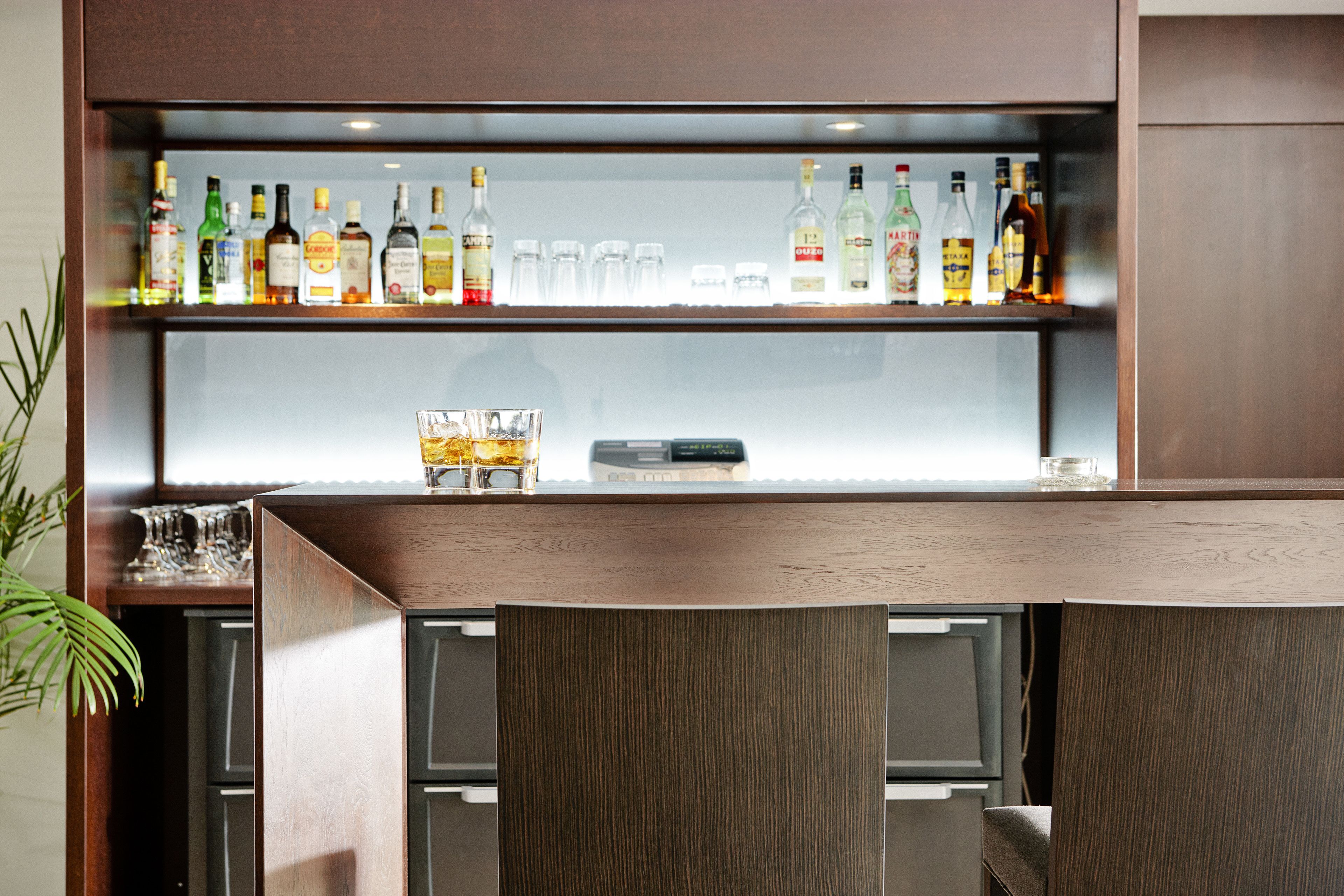A bar area with a wooden counter and shelves displaying various liquor bottles.