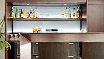 A bar area with a wooden counter and shelves displaying various liquor bottles.