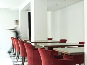 Un área de comedor moderna con sillas tapizadas en rojo y mesas de madera.