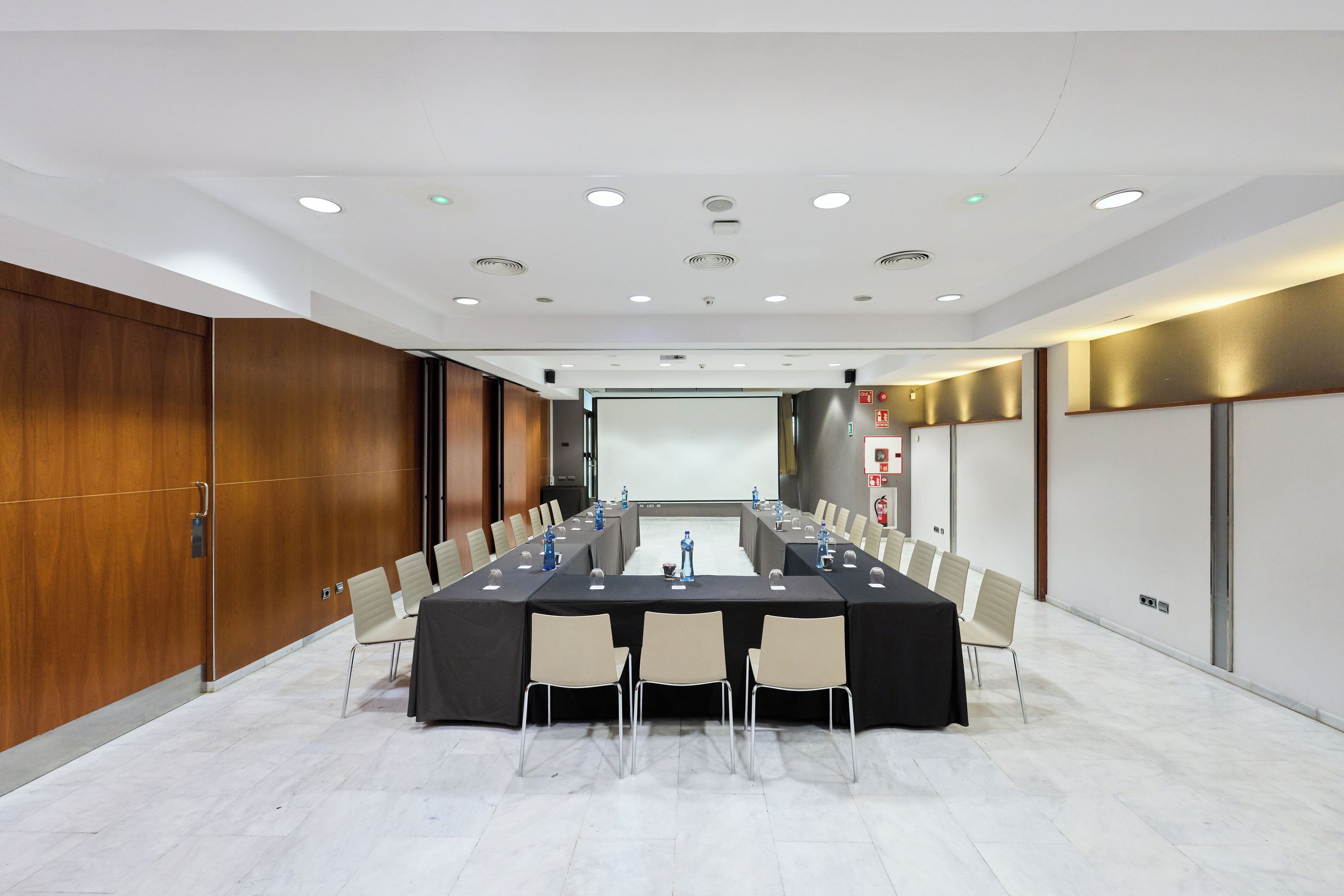 Una sala conferenze con un lungo tavolo, sedie, uno schermo per proiettore e una lavagna.