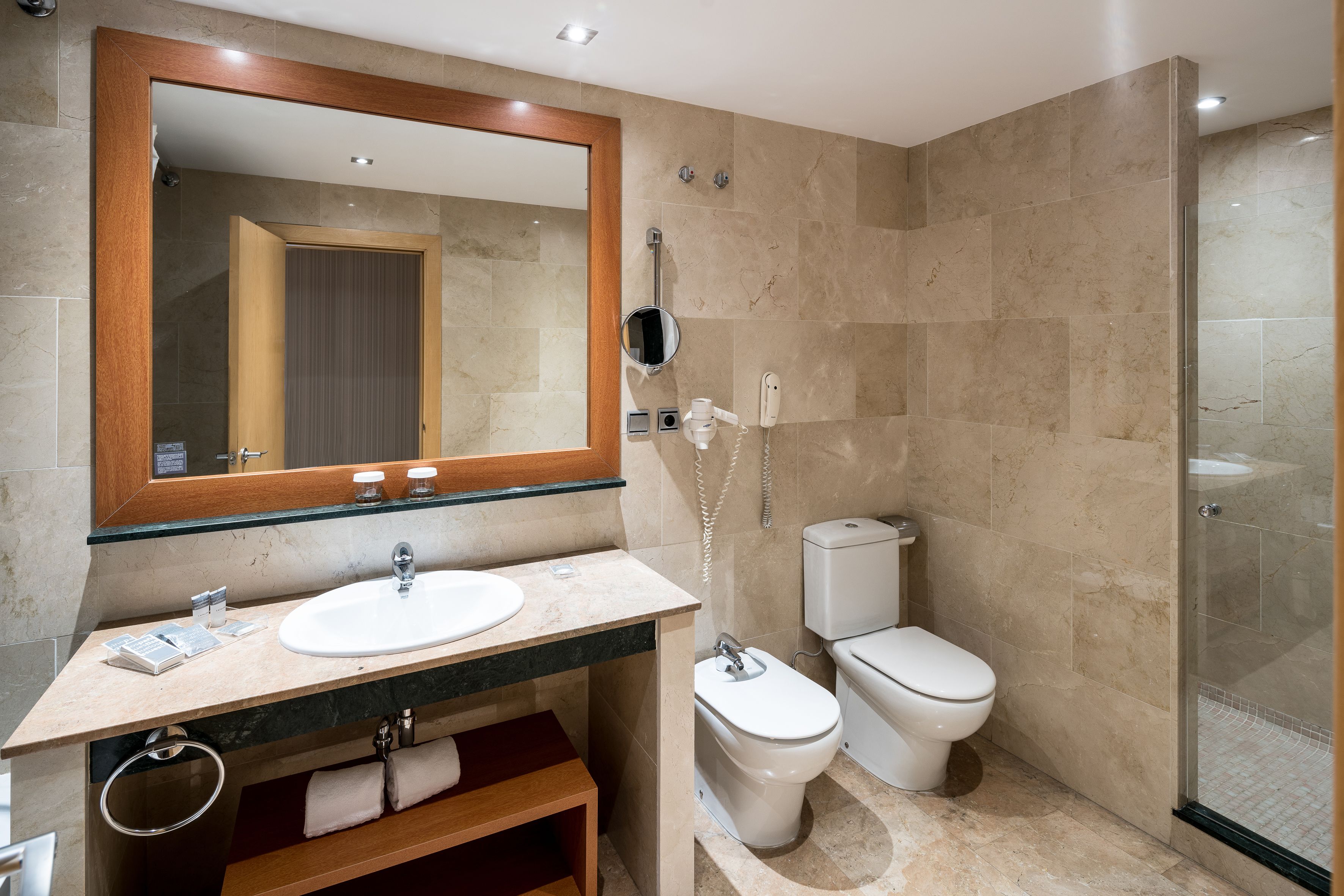 Une salle de bain moderne avec un grand miroir, un lavabo, des toilettes et un espace douche.