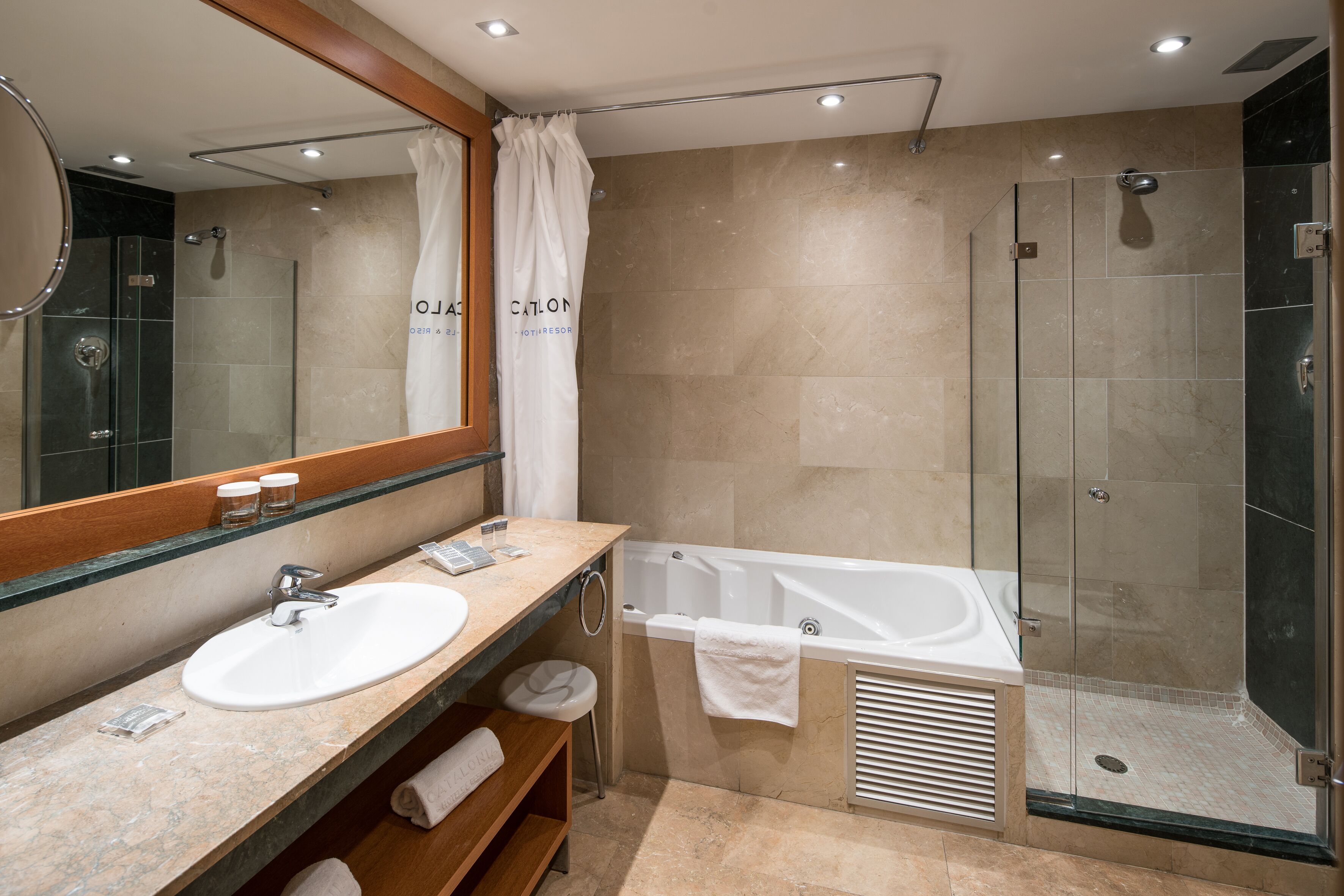 A modern bathroom with a sink, mirror, vanity, shower, and bathtub.