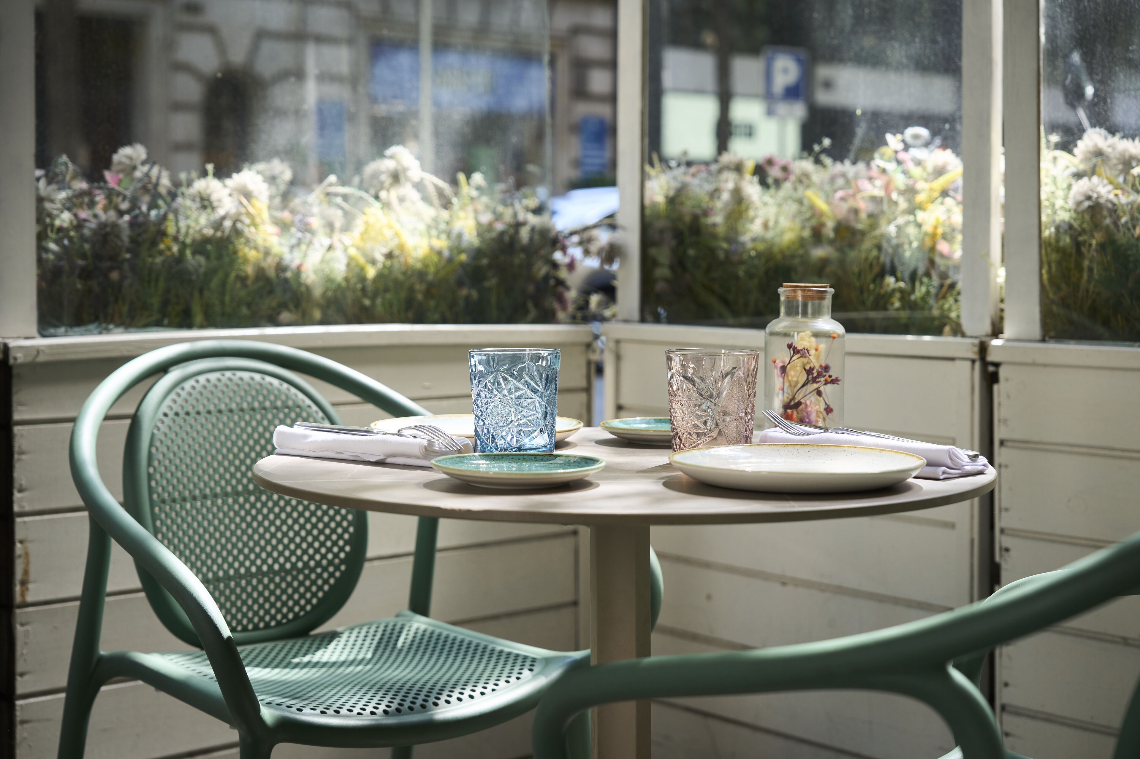 A table set with plates, glasses, and a vase with flowers.