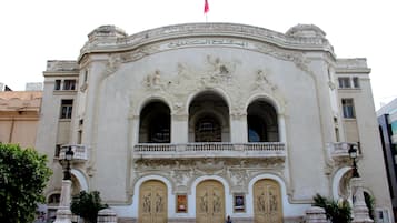 Un edificio histórico con elaboradas esculturas, un balcón y tres puertas grandes.
