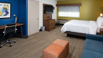 Ein Hotelzimmer mit Bett, Schreibtisch, Stuhl, Fernseher und einem Vorhangfenster.