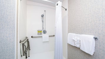 A shower area with a handheld showerhead, a glass shower enclosure, and a towel rack with towels.