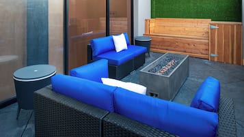 An outdoor seating area with wicker furniture and a built-in fire feature.