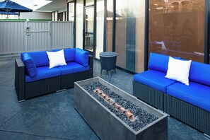 Two blue sofas with white cushions, a rectangular fire pit, and a small round table. - Holiday Inn Express & Suites Los Angeles Downtown West by IHG (Los Angeles)