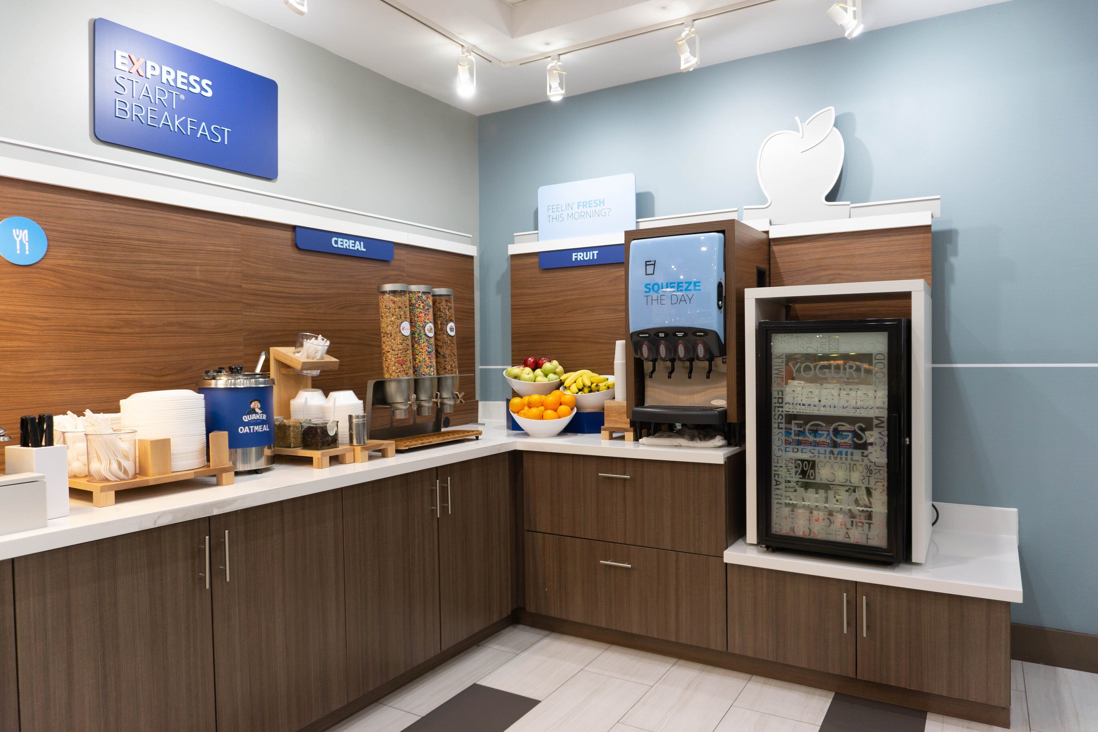 A breakfast area with a sign for 'Express Start Breakfast', a fruit display, and a yogurt dispenser.
