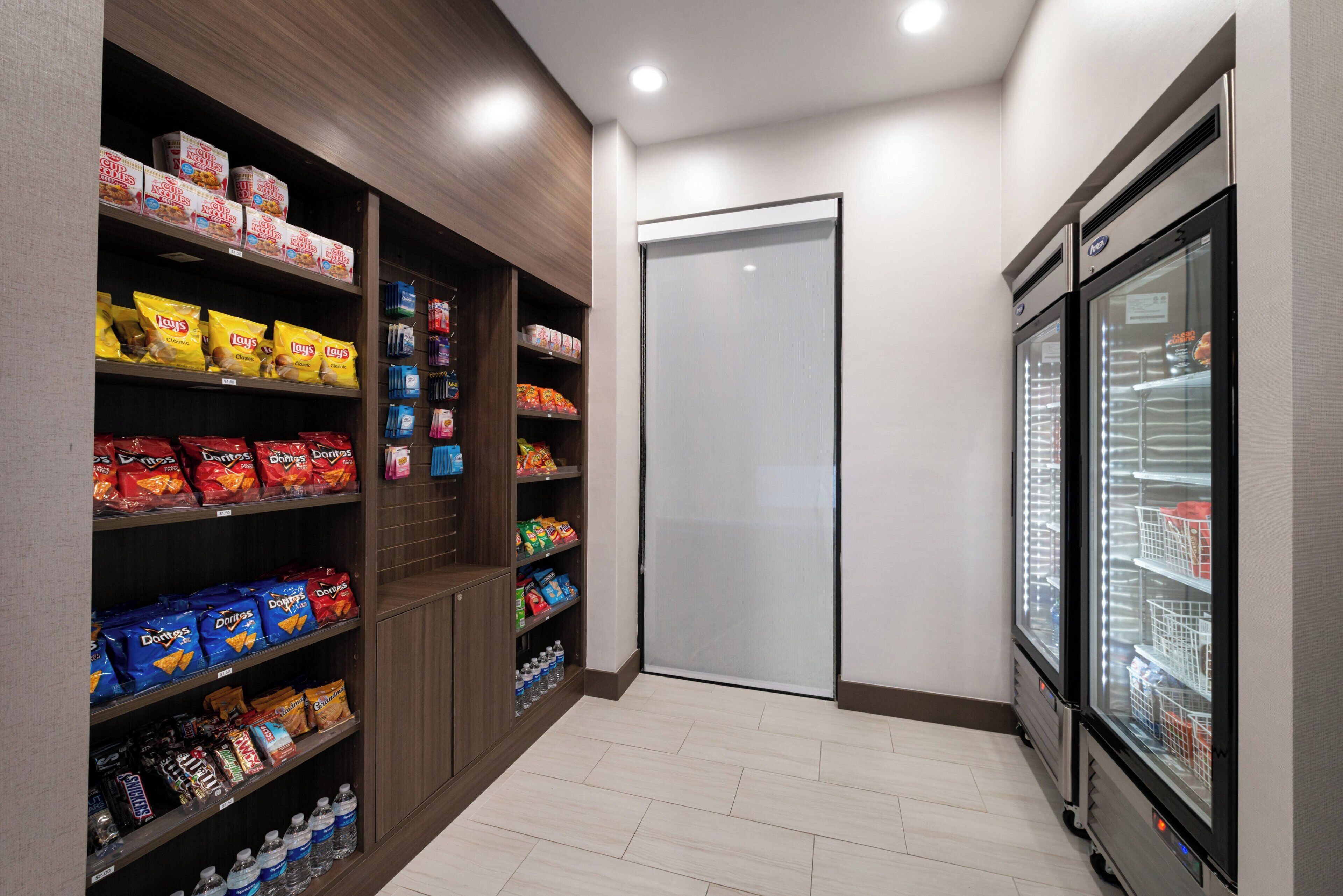 Ein Verkaufsregal mit verschiedenen Chips und Snacks, ein Wasserkühler und ein Kühlschrank.