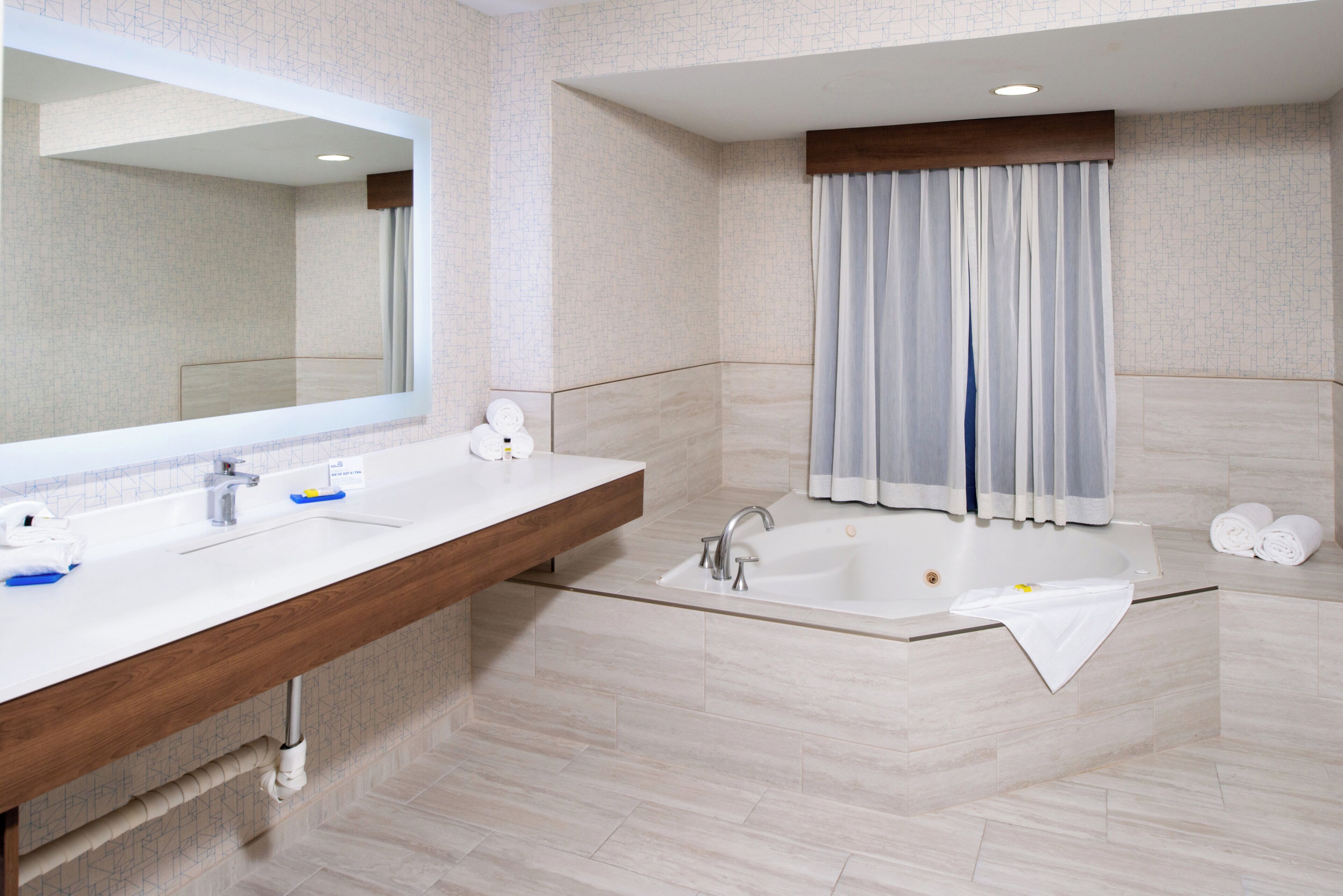 A modern bathroom with a double sink vanity, a large mirror, a freestanding bathtub, and a shower area.