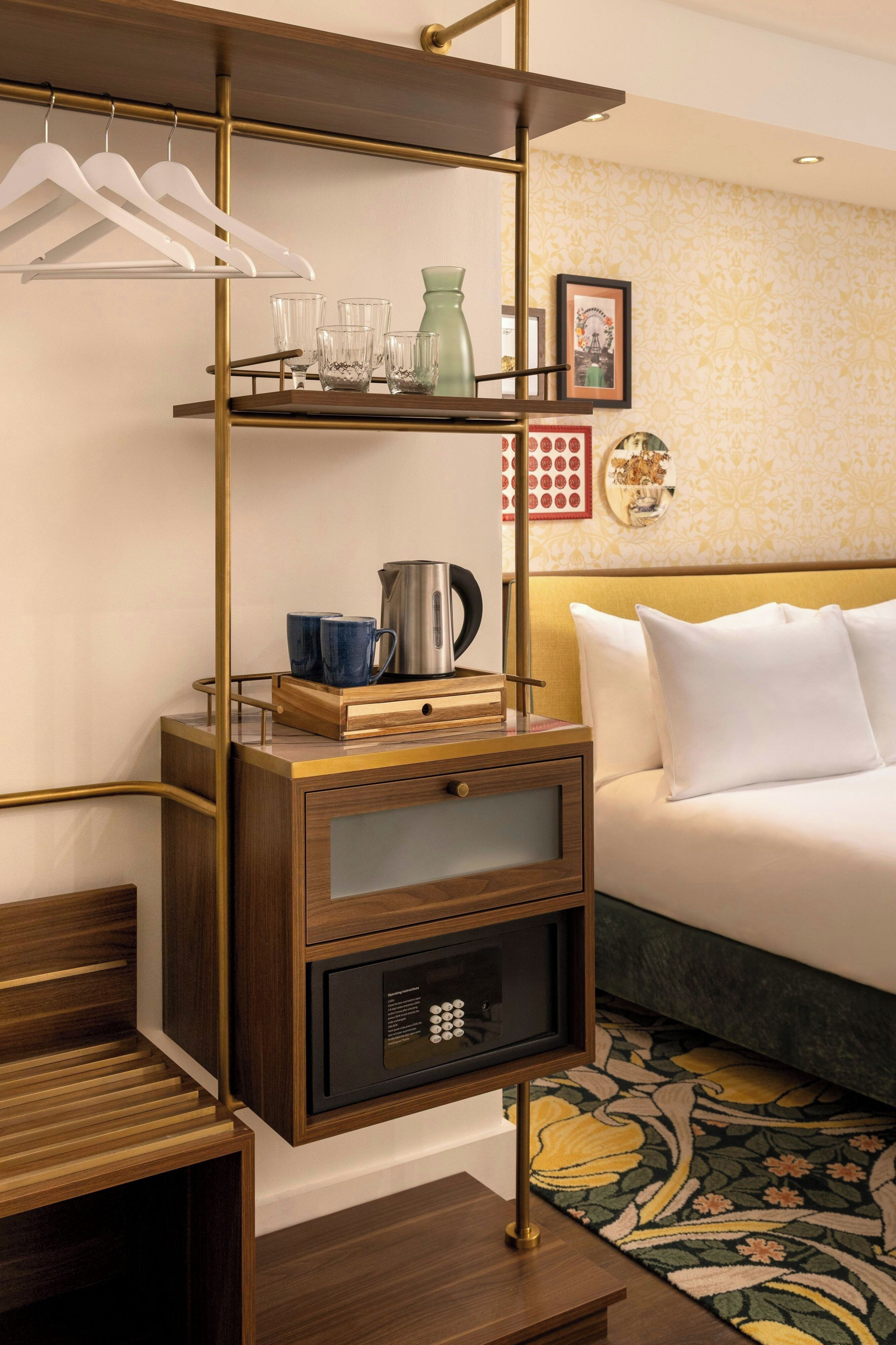 Une chambre d’hôtel comprenant un lit, une table de chevet avec une bouilloire, un plateau et une petite armoire fermée à clé.