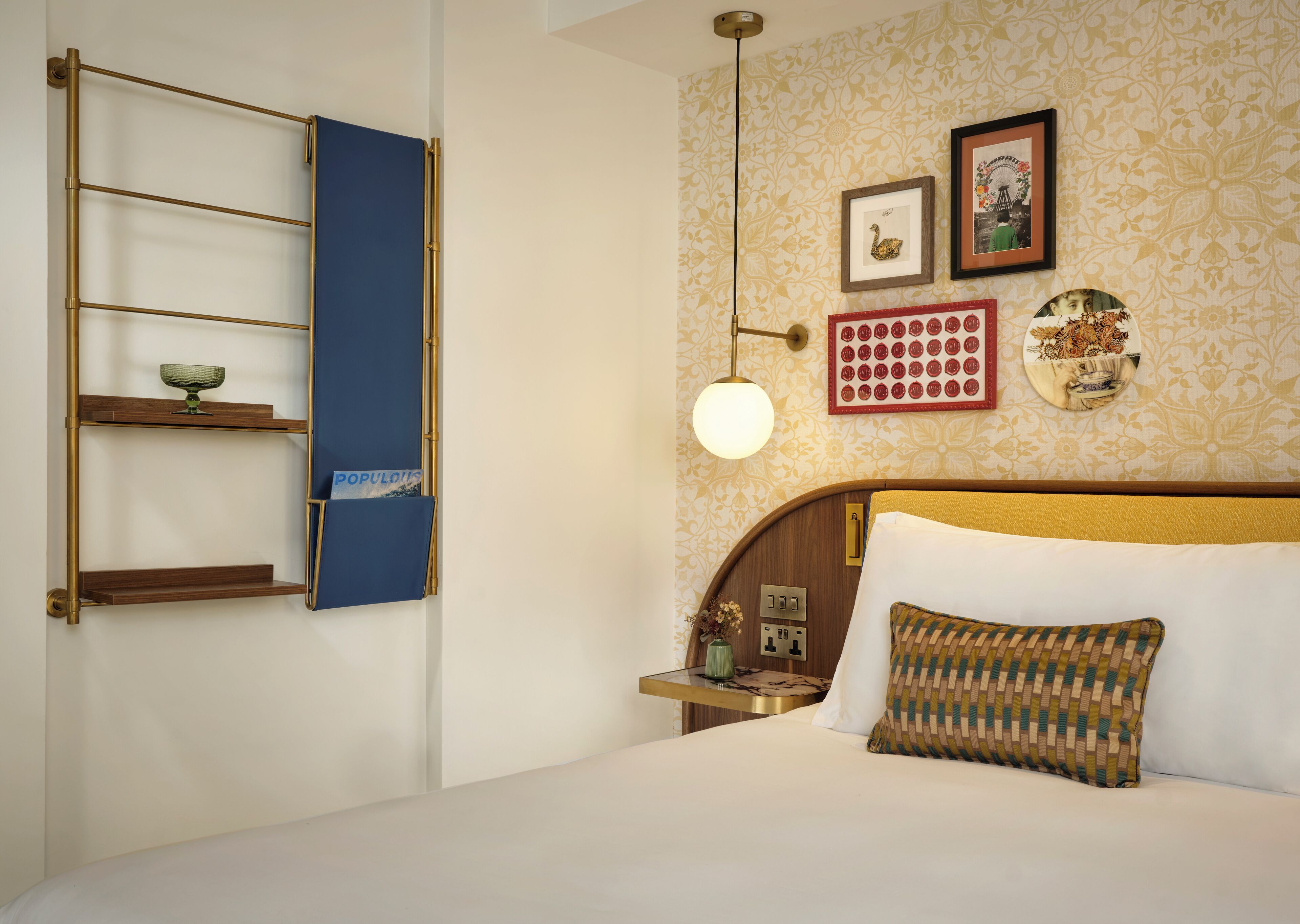 Quarto de hotel com uma cama, uma estante, um relógio de parede e objetos decorativos.