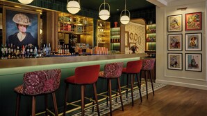 Zona de bar con mostrador, varios taburetes y una variedad de botellas y vasos.