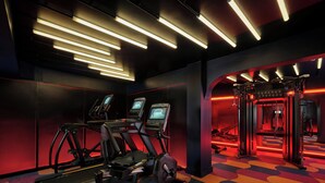 Un gimnasio con cintas de correr, elípticas y una alfombra colorida.