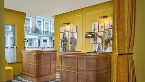 Un vestíbulo de hotel con mostradores de recepción de madera, suelo a cuadros y cuadros en las paredes.