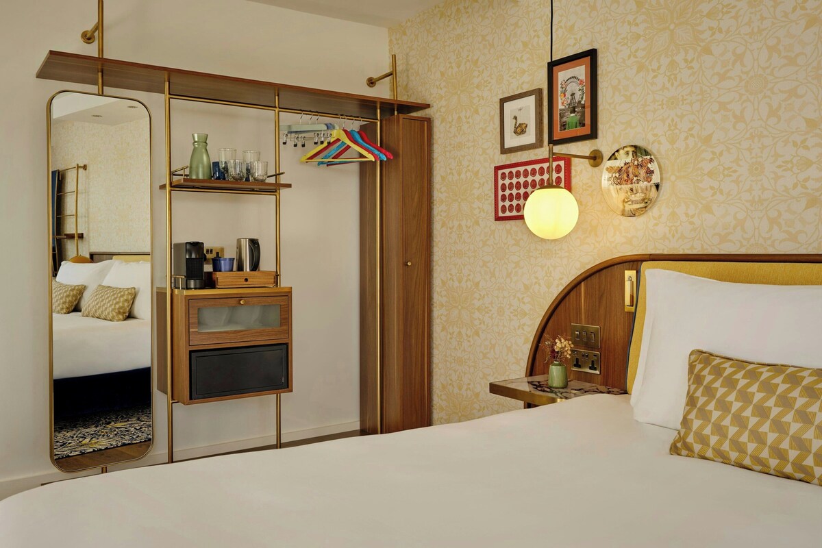 Ein Hotelzimmer mit Bett, Schrank, Spiegel, Nachttisch und einer Wand mit Dekoration.