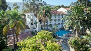 A multi-story building with a swimming pool, surrounded by lush greenery and palm trees. - Catalina Canyon Inn (Avalon)