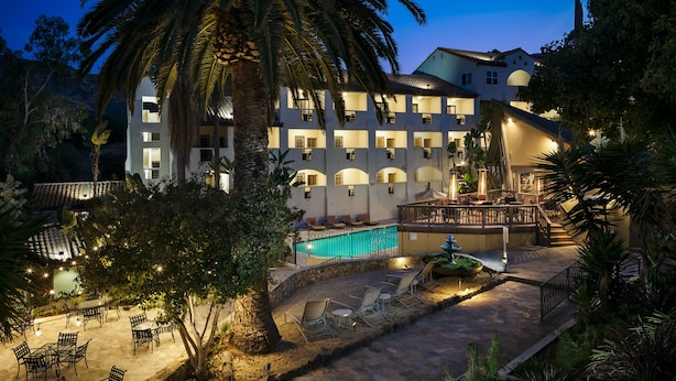 A hotel with a pool, outdoor seating, and a well-lit patio area. - Catalina Canyon Inn (Avalon)