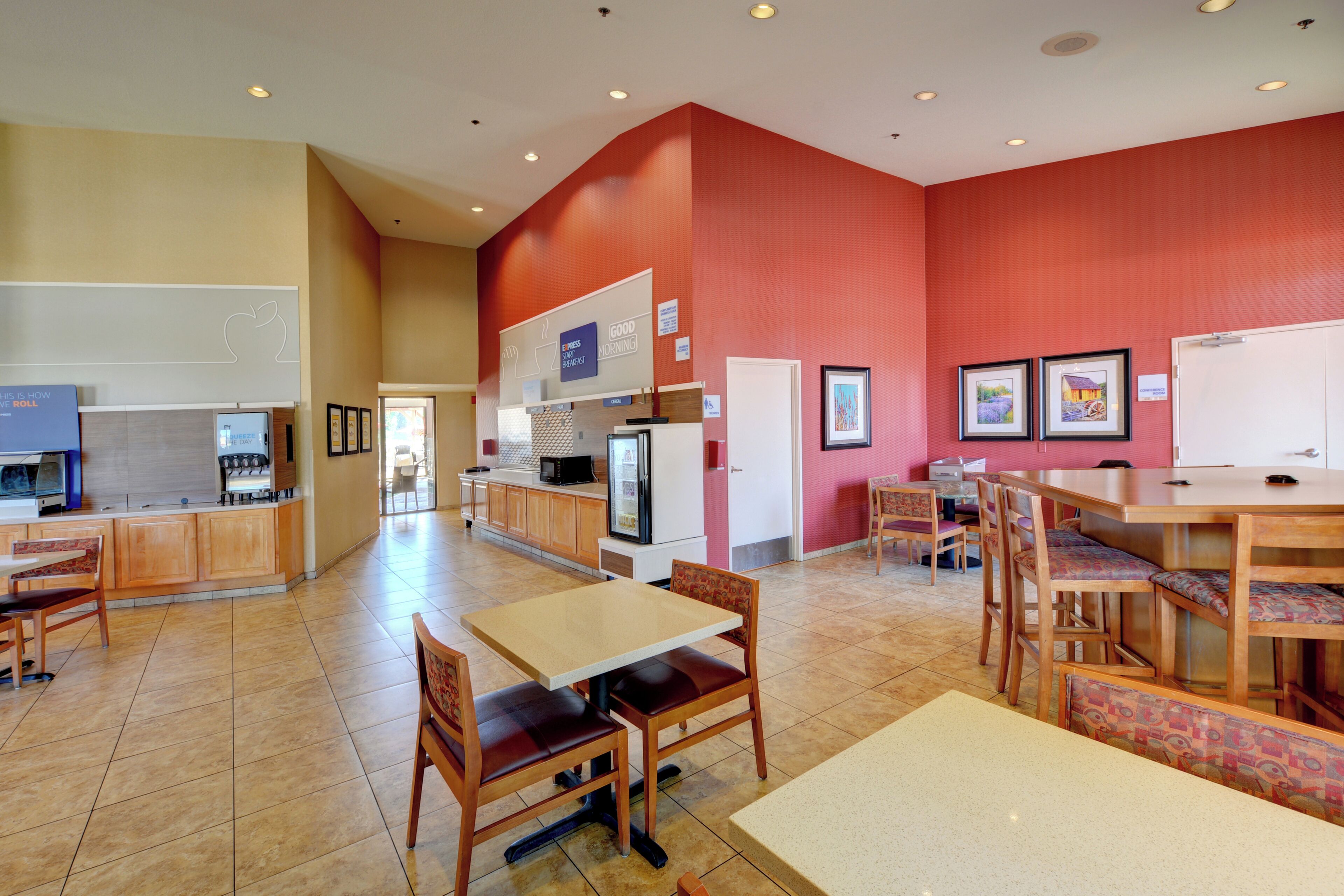 A modern kitchen with a microwave, coffee maker, and refrigerator. There are wooden cabinets and a sink.