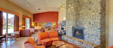 A spacious living area with orange sofas, a stone fireplace, and a dining area with a large table and chairs.
