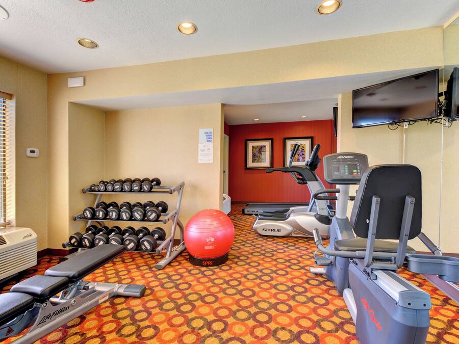 A gym with exercise equipment, a treadmill, dumbbells, and a stationary bike.