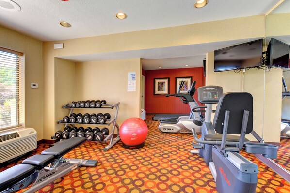 A gym with exercise equipment, a treadmill, dumbbells, and a stationary bike.