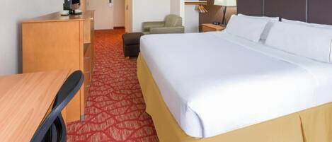 A hotel room with a bed, a desk, a chair, a TV, and a lamp.